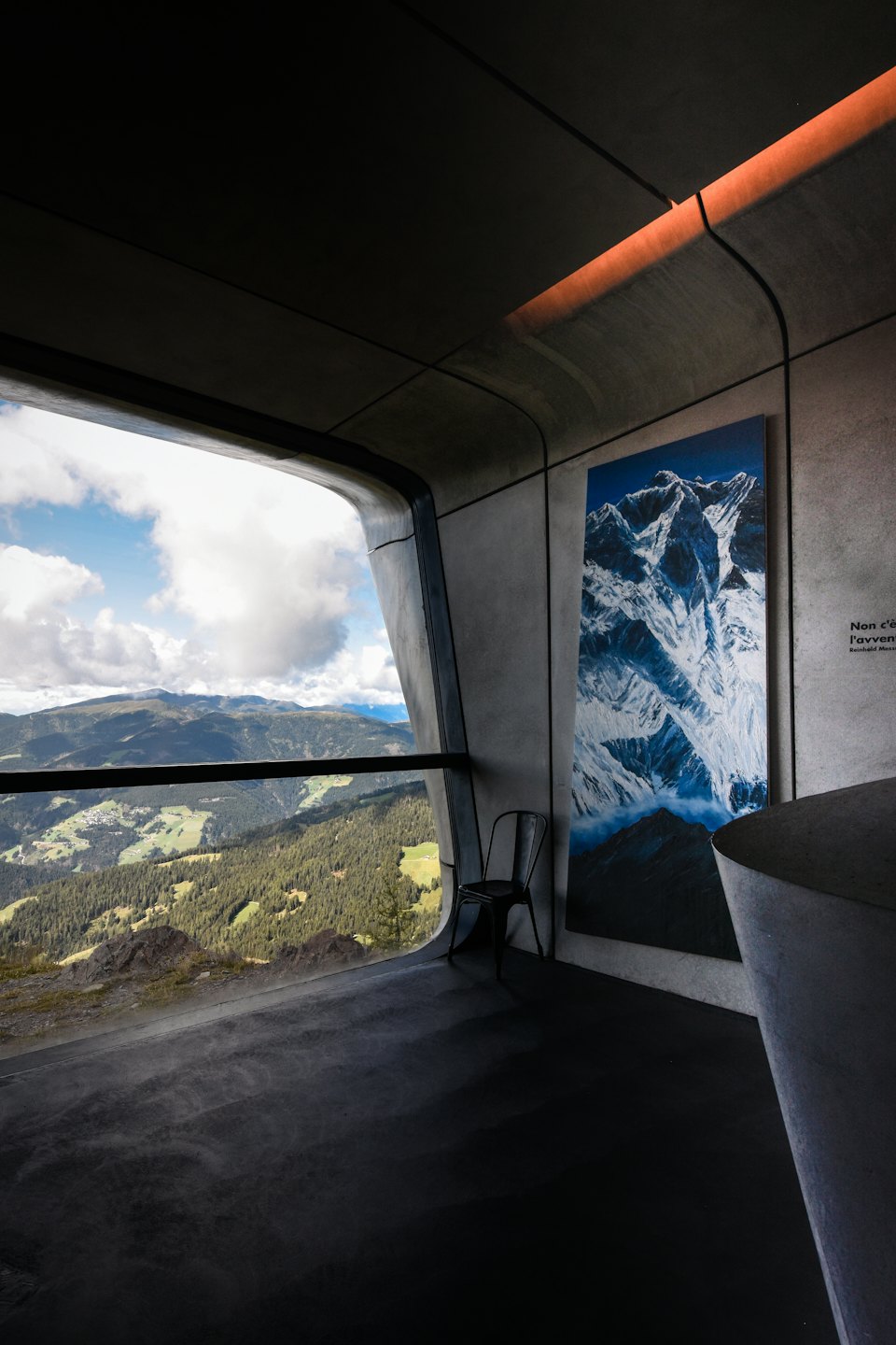 Stanza moderna con pareti in cemento e vista sulle montagne.